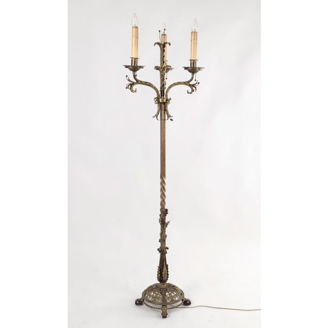 Victorian Revival brass three arm candelabra floor lamp with a twisted column, openwork base, scrolled metalwork, and...