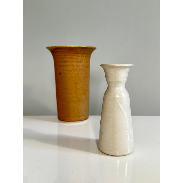 Beautiful pair of hand-thrown vases in rust red and cream white. Larger vase, a cylindrical shape widening towards the top...
