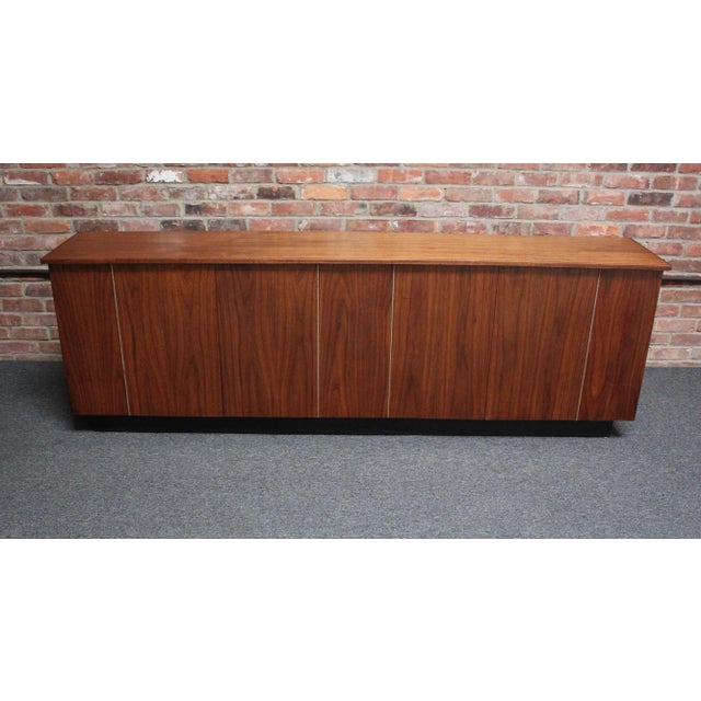 American Modern custom-made walnut credenza/cabinet in walnut supported by an ebonized plinth base (ca. 1960s/70s)....