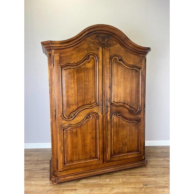 An elegant Vintage French oak wardrobe with two large panelled doors, a sweeping curved top and decorative detailing that...