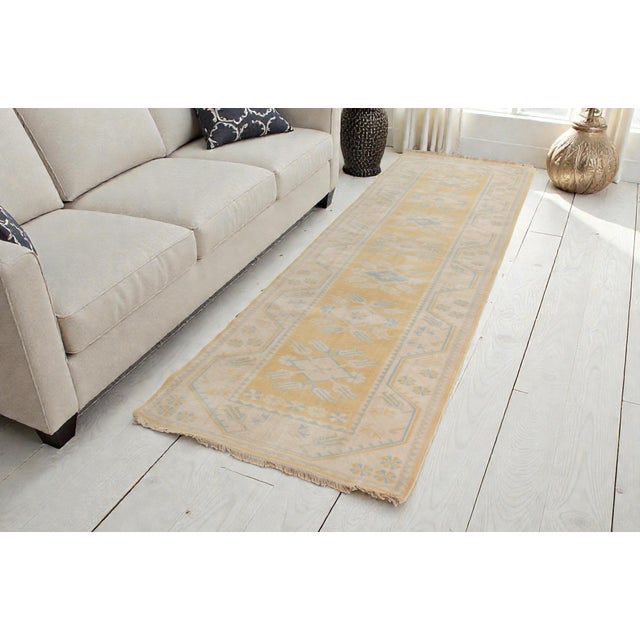 This is a vintage Turkish Oushak rug from the Mid 20th Century. The piece was hand-knotted.