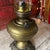 This antique brass oil lamp features intricate Victorian designs on its ornate base and a clear glass chimney. A...