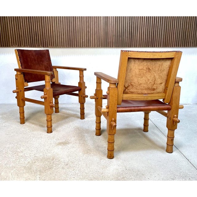 This set of two brutalist leather safari chairs was manufactured in Colombia during the 1960s. These pieces feature...