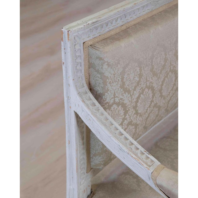 Made in Sweden around 1840, this carved pine bench retains its worn, old grey paint and an upholstered seat. The carving...