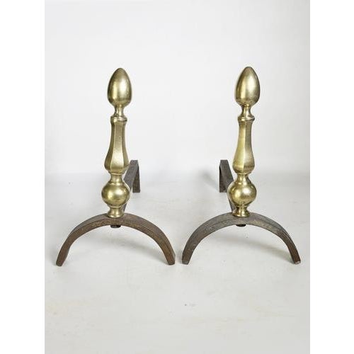 Pair of andirons with brass finials, France, 1930s, featuring an elegant and timeless design. These pieces are...
