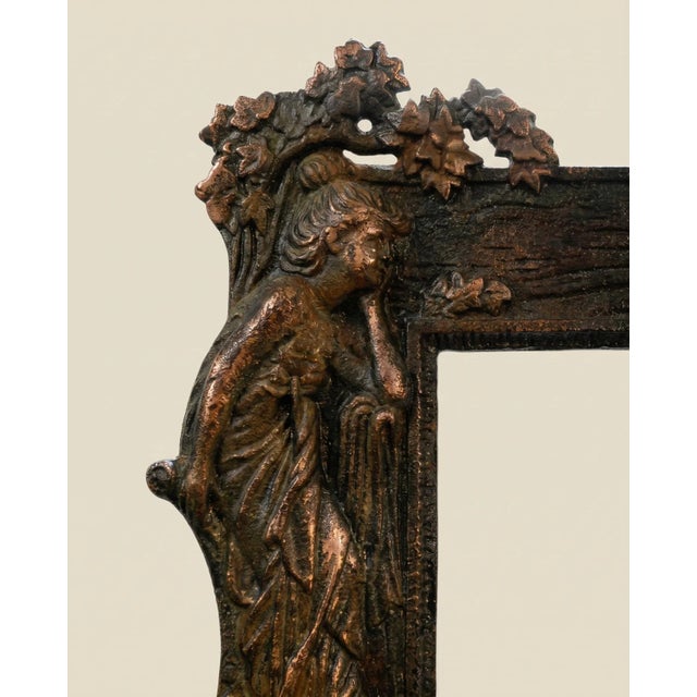 An elegant antique Art Nouveau picture frame featuring a graceful female figure surrounded by flowing botanical forms and...