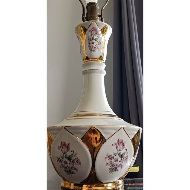 Elegant vintage ceramic table or bedside lamps featuring a glossy ivory-white finish, ornate gold-tone accents, and...