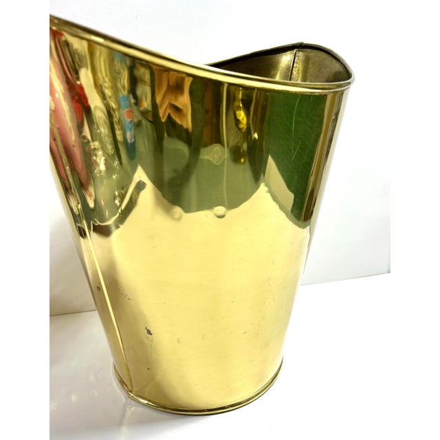 A polished English brass wastebasket or cachepot with a softly tapered silhouette, lightly hammered interior, and classic...