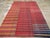 This mid-20th century Turkish flatweave kilim rug, features a vibrant composition of horizontal stripes woven across three...