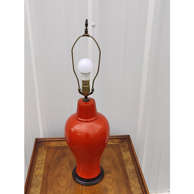 A handsome orange art pottery table lamp with with black finished base that measures 29" up to finial and 6" diameter at...