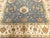 Handmade wool rug featuring an ornate floral and botanical palmette motif with a blue field and contrasting ivory border....