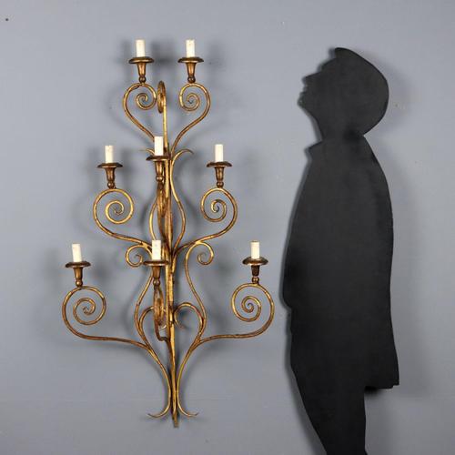 Pair of gilded iron wall sconces. Eight lights arranged on a triple tier, supported by curved arms with curlicues. Gilded...