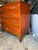 This antique Mahogany Federal Style chest of drawers features splayed feet, a solid pattern, and a brass handle finish....