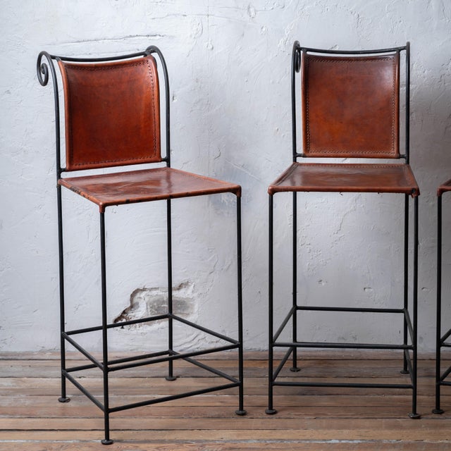 A set of four spanish hacienda wrought iron and leather counter stools, 1960s. 17 inches wide by 23 inches deep by 41...