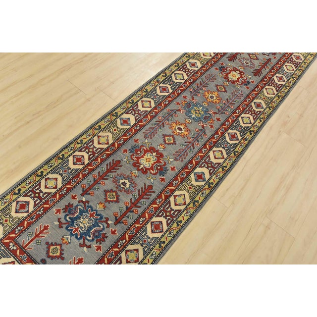 A tribal Caucasian Kazak runner hand-knotted with fine wool on a cotton foundation. This rug features a row of medallions...
