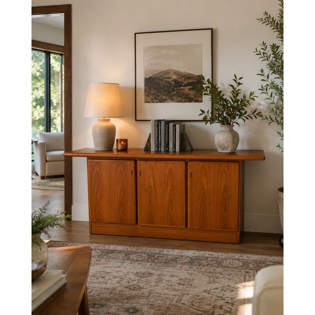 Vintage Boltinge sideboard is crafted from teak wood with a warm honey finish. This Danish-made piece has three cabinet...