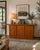 Vintage Boltinge sideboard is crafted from teak wood with a warm honey finish. This Danish-made piece has three cabinet...
