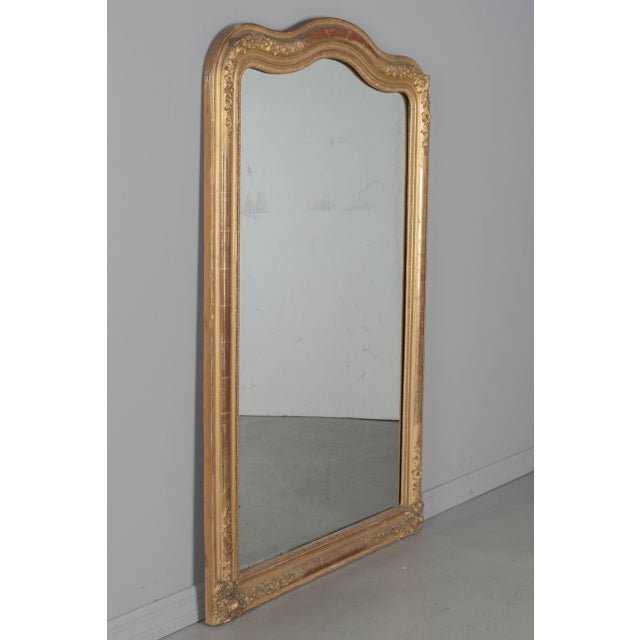 A 19th century Louis Philippe style French gilded mirror with shaped top and floral decorations in the corners. Gilt...