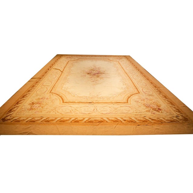 This circa 1850 French Aubusson rug is an authentic 12' 8" x 18' 2" flatweave masterpiece featuring a beige field and a...
