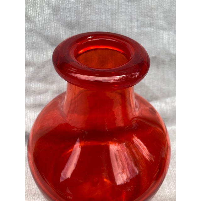 Vintage chunky, reddish orange Kosta Boda bottle. It measures 6 3/4" in diameter by 9 1/2" in height. Minor scratches on...