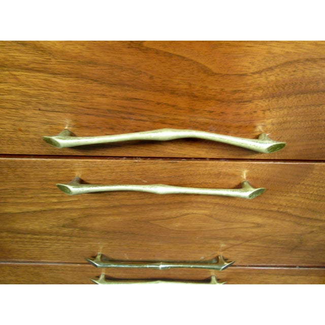 This odd walnut credenza features twelve drawers with doors that cover three per side, it also has sleek brass handles...