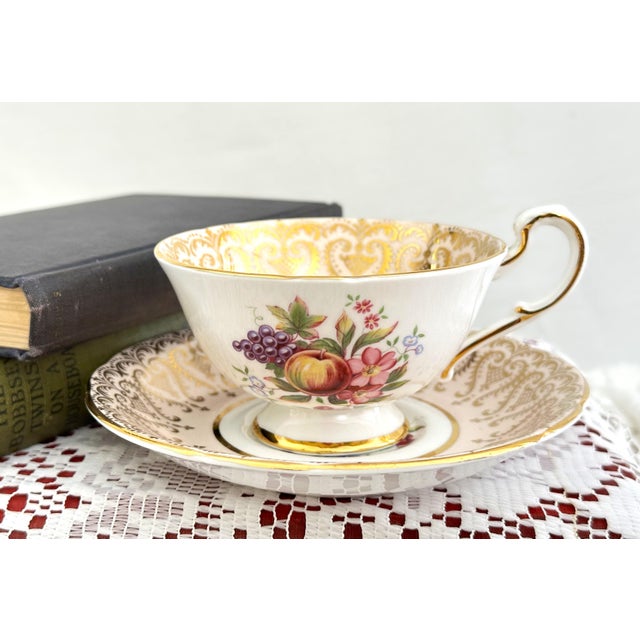 This vintage fine bone china teacup and saucer set was crafted by Paragon in Staffordshire, England. Molded into the...