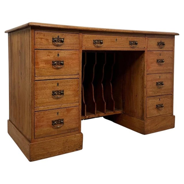 A handsome 19th-century English kneehole desk, finely crafted from pine and distinguished by its extensive nine-drawer...