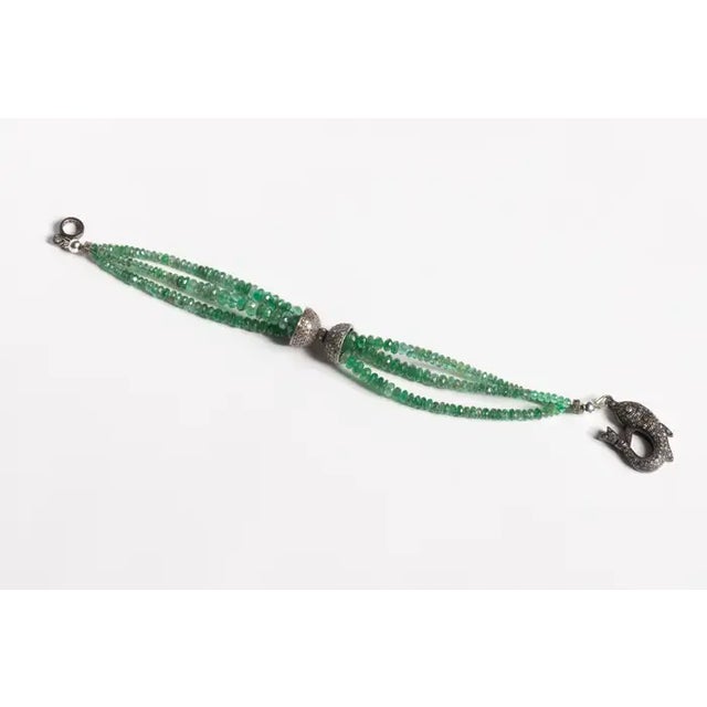 A triple strand of faceted Columbian emerald beads with a fish motif clasp with pave`-set diamonds and a double cap top...
