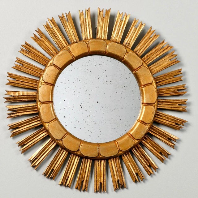 Giltwood mirror in sunburst form has rays with jagged tips and an incised scallop design on the inner frame, circa 1960s....