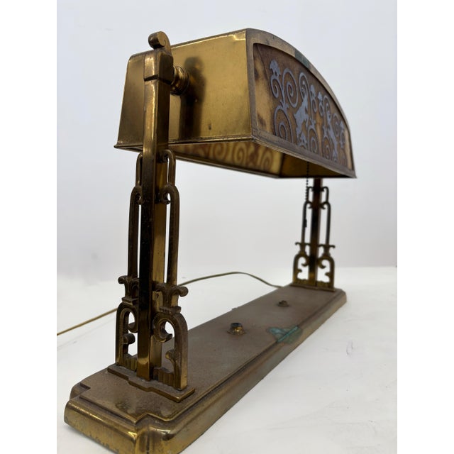 early 20th-century bronze table or desk lamp featuring a stylized rams head motif and an acid-etched glass shade. Strong...