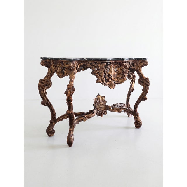 A dramatic and finely carved 19th century Italian Baroque console table featuring an ornately sculpted giltwood base and...