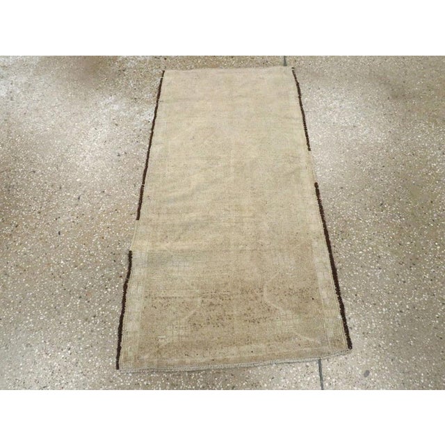 This Early 20th century Turkish Oushak rug, measuring 1' 10" x 3' 9", captures the understated beauty and refined elegance...