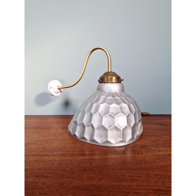 Wall sconce with a mercury glass globe produced by the english manufacturer helioray, and a brass and porcelain gooseneck...