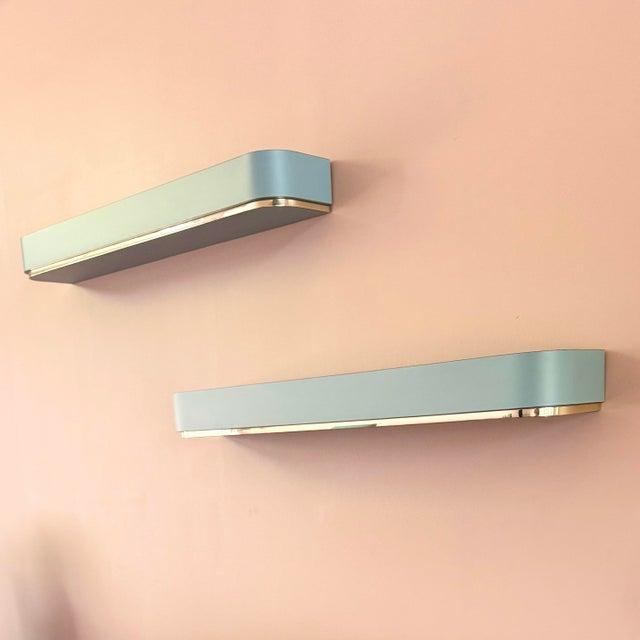 A striking pair of Postmodern floating wall-mounted sconce shelves, finished in an elegant baby blue laminate with sleek...