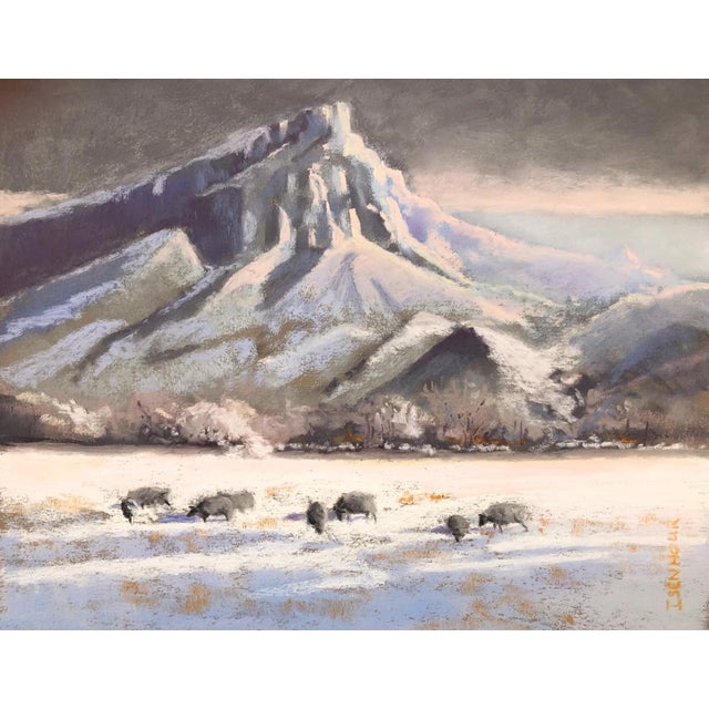 This pastel work depicts a serene winter landscape, featuring a majestic mountain backdrop and a herd of bison grazing in...