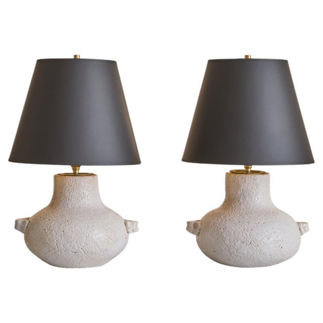A French white ceramic table lamp from the 1960s, distinguished by its softly rounded, vessel-like form and tactile...