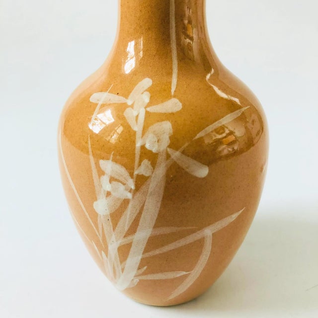 A vintage ceramic vase with a lovely hand painted iris design in white over a light tan base glaze.