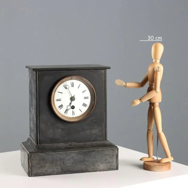 Black marble table clock. Enamelled metal dial with Roman numerals, protected by a glass cover. This piece is attributed...