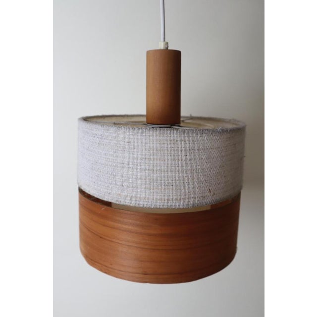 This beautifully simple Scandinavian pendant lamp is a unique combination of a wool-like fabric and teak plywood. Designed...