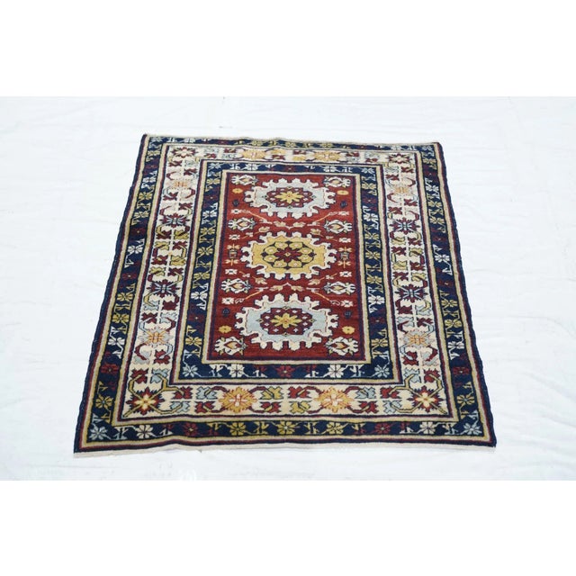 The deep wine red field presents three ragged cogwheel ellipses in ecru, powder, straw and red, seconded by petal...