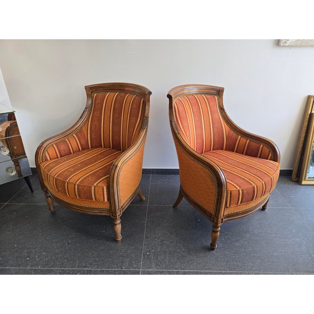 A beautiful pair of enveloping bergère armchairs, from a high-quality furniture manufacturer, bearing an elegant metal...
