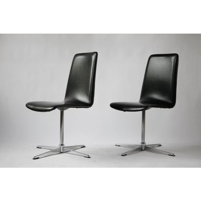 Vintage pair of swivel chairs dating from the 1970s. Both chairs retain their original black vinyl upholstery. A versatile...