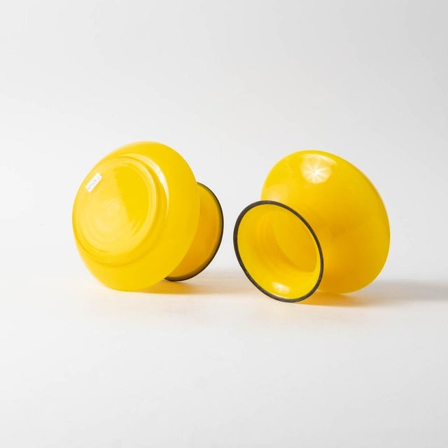 Pair of tango style glass vases. Made of yellow glass with black painted rim. Produced in 1920s in former Czechoslovakia....