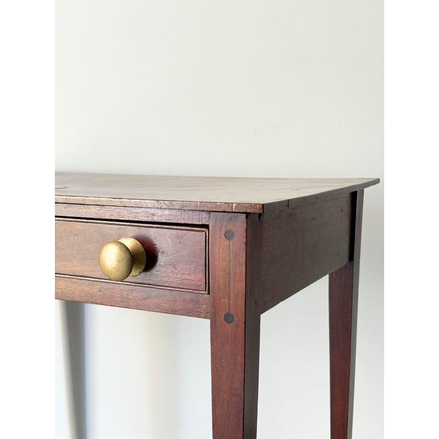 A 19th century wooden side table with geometric inlay detail, elegant tapered legs, a single drawer and brass handles....