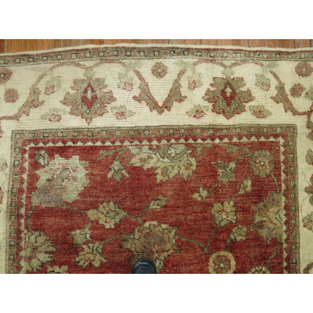 A 20th century Turkish Oushak with a crimson red all over motif, ivory border accents in brown Measures: 5'3" x 9'11''....