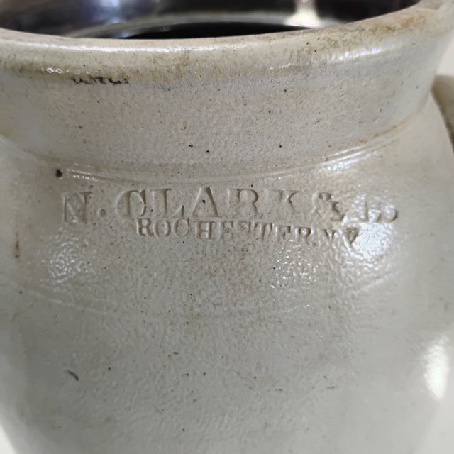 This piece is an antique salt-glazed stoneware crock stamped with the maker's mark N. CLARK & Co. / ROCHESTER N.Y.,...