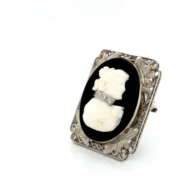 This exquisite vintage cameo brooch and pendant is crafted in elegant 14k white gold with a refined floral filigree and...