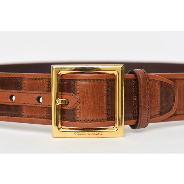 This fabulous never worn Italian Dolce and Gabbana leather belt has a brass buckle with 2 shades of brown leather. The...