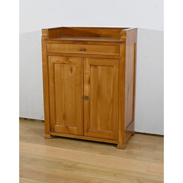Community furniture in blond cherry, dating from the end of the 19th century. This tall and narrow sideboard has a...