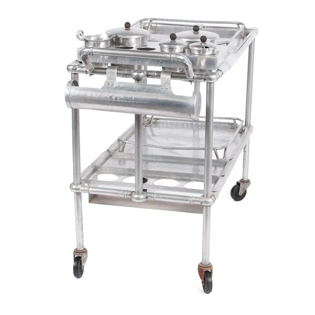 American, 1940s, aluminum hand-wrought and tubular construction cart with lift-out trays of foliate motifs, and inset...